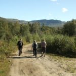 three people walking on gravel road