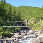 person crossing bridge over river