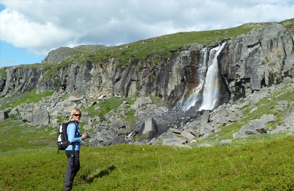 woman hiking with waterfall in the background