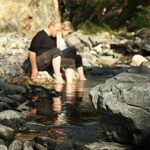 two people dipping their feet in a river