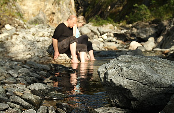 two people dipping their feet in a river