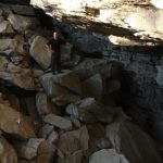 man standing in cave with big rocks