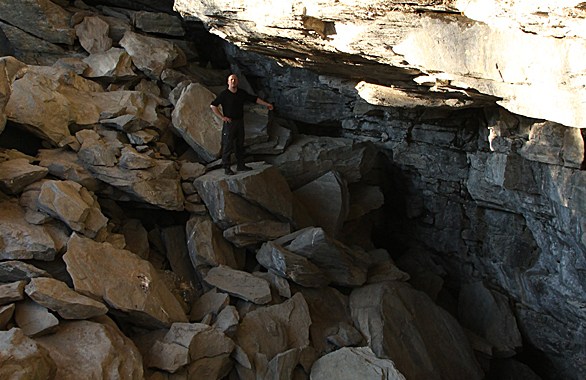 man standing in cave with big rocks