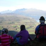 three people enjoying the view from a mountain