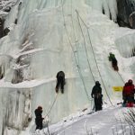 several people climbing up ice wall