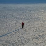 person standing in flat snowy field