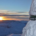 sign on top of mountain covered in snow